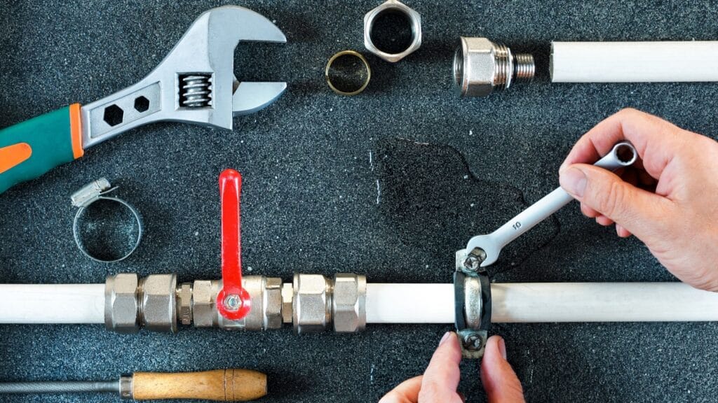 Plumber repairing a pipe valve with an adjustable wrench in Miami Gardens