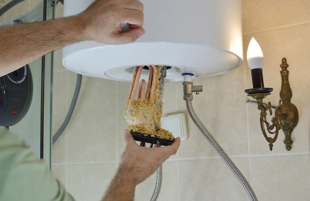 Technician removing mineral buildup from a water heater in Miami Gardens