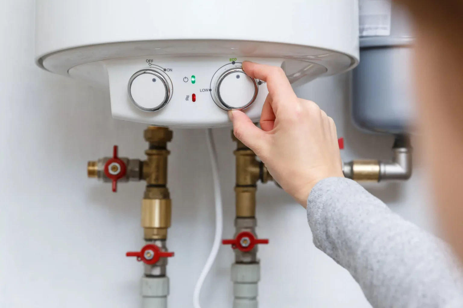 Homeowner adjusting the temperature controls on a water heater in Miami Gardens